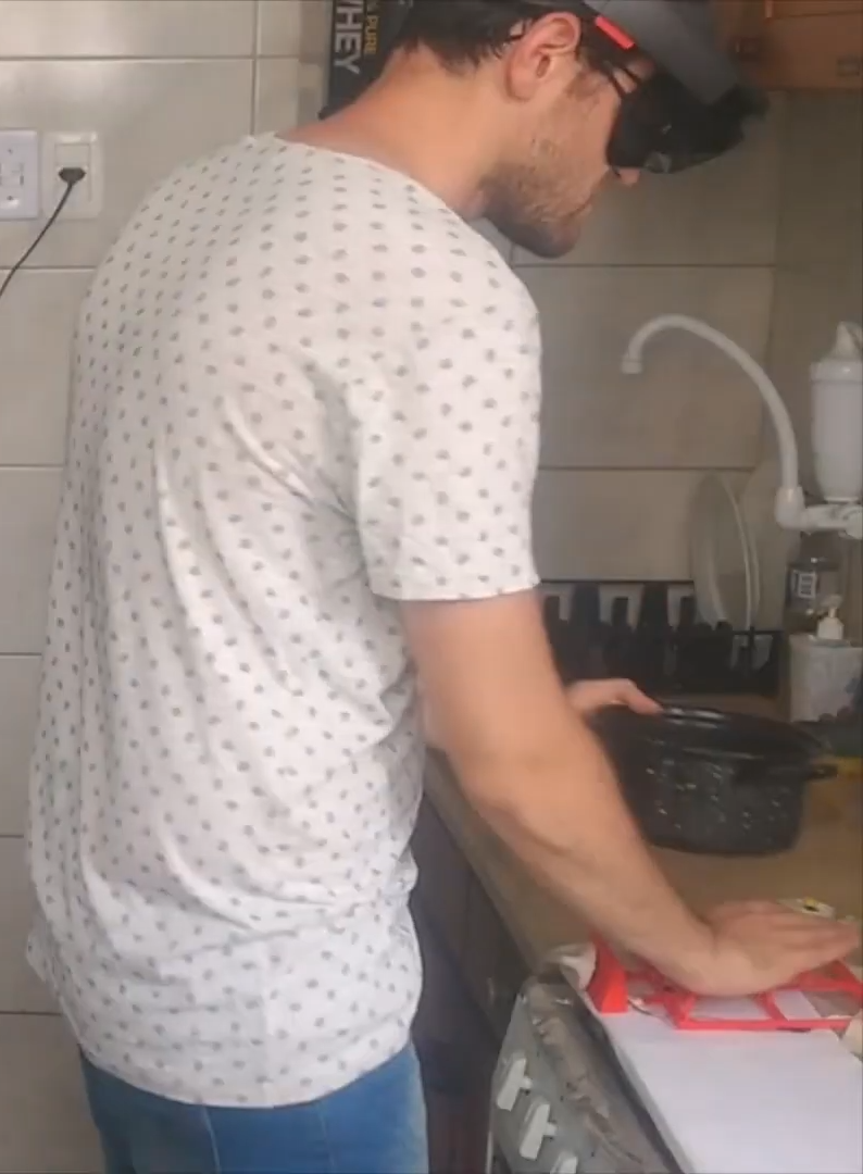 Blindfolded user wearing an augmented reality headset while holding a pan and searching for a stove